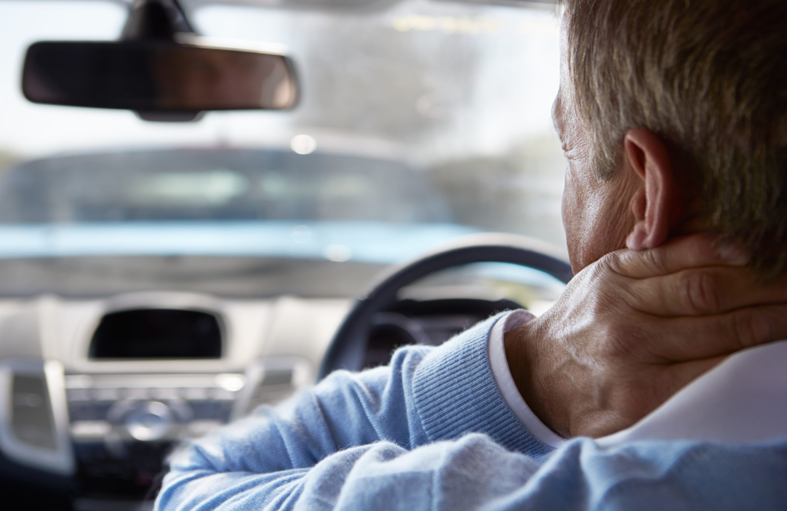 A man holding his neck after getting whiplash in a car accident.