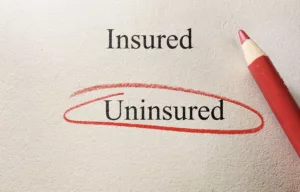 A Red Pencil Circles The Word “Uninsured” Beneath The Word “Insured” On A Printed Document, Symbolizing The Complications Of Dealing With Coverage Gaps And The Importance Of Contacting An Arlington Uninsured Motorist Lawyer For Legal Guidance.