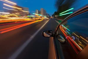 Car Driving At High Speed Through A City At Night With Light Trails In Motion, Depicting Scenarios Where An Arlington Speeding Accident Lawyer Can Provide Legal Support.