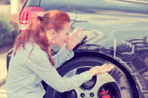 Upset Woman Inspecting Damage To Her Car After A Hit And Run Accident, Symbolizing The Need For A Fort Worth Hit And Run Lawyer.
