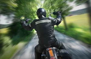 A Motorcyclist Speeds Down A Rural Road In Full Protective Gear, Illustrating The Type Of Serious Crashes A Grand Prairie Motorcycle Accident Lawyer Can Help Victims Recover From.
