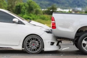 A White Sedan Has Collided With The Back Of A Silver Pickup Truck On A Roadway, Showing Visible Front-End Damage—Underscoring The Commonality Of These Crashes And The Need For An Arlington Rear-End Collision Lawyer To Help Victims Navigate The Claims Process.
