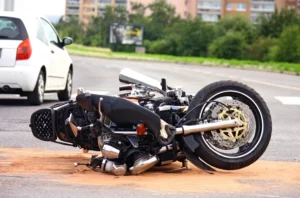 A Damaged Motorcycle Lying On Its Side In The Middle Of A Fort Worth Intersection Following A Collision, Emphasizing The Need For A Fort Worth Motorcycle Accident Lawyer To Help Injury Victims Pursue Compensation.