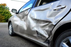 Damaged Silver Sedan With Severe Side Impact Dents, Commonly Seen In T-Bone Collisions — Consult A Grand Prairie Car Accident Lawyer For Legal Help.