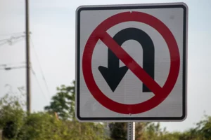 A “No U-Turn” Traffic Sign Stands Beside A Rural Road, Emphasizing The Risks Of Illegal Maneuvers And The Need For A Skilled Dallas U-Turn Accident Lawyer To Help Victims Pursue Justice After A Crash.