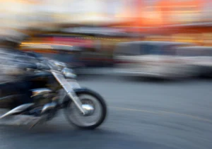 A Blurred Motorcycle Speeds Through A Busy Urban Street, Representing Common Causes Of Motorcycle Accidents In Dallas Such As Driver Inattention, Speeding, And Unsafe Lane Changes.