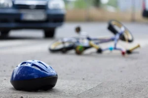 Blue Bicycle Helmet On The Ground Near A Damaged Bike And Car, Representing The Aftermath Of A Crash; Ideal Visual For A Cockrell Hill Bike Accident Lawyer.