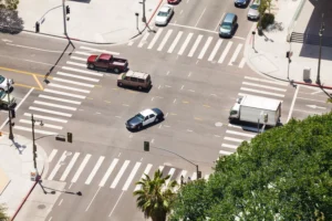 A Busy Urban Intersection With Multiple Vehicles, Including A Police Car And A Truck, Navigating Through Crosswalks And Traffic Signals. Contact A Dallas Intersection Car Accident Attorney For Legal Help After An Accident At Intersections Like This.