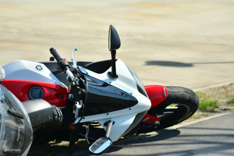 Motorcycle crash scene on a city street showing where do most motorcycle accidents occur, with the bike lying on its side near the curb.