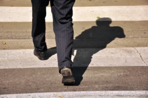 Close-Up Of A Person In Dress Shoes Crossing A Street At A Crosswalk In Grand Prairie, Representing A Scenario Often Handled By A Grand Prairie Pedestrian Accident Lawyer.
