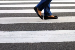 Person Crossing A Street In Lancaster, Texas, Highlighting The Importance Of Hiring A Lancaster Pedestrian Accident Lawyer For Injury Claims.
