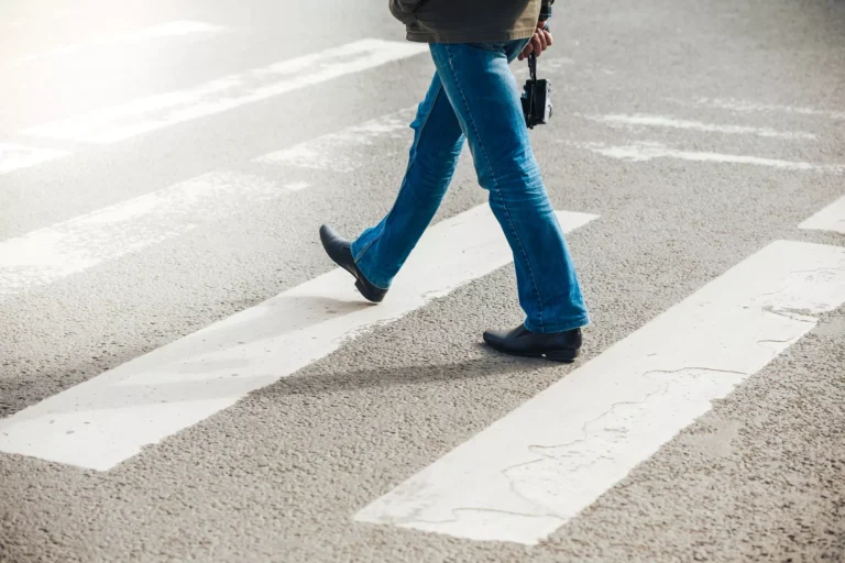 Pedestrian crossing at a marked crosswalk, representing the question: do pedestrians have the right of way in Texas?