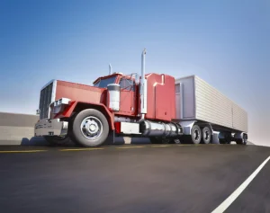 Red 18-Wheeler Driving On A Highway Under A Clear Sky, Representing The Types Of Cases Handled By A Dallas Truck Accident Lawyer.