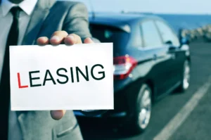 Man Holding A Sign That Says Leasing In Front Of A Parked Car, Representing What Happens If You Crash A Leased Car.