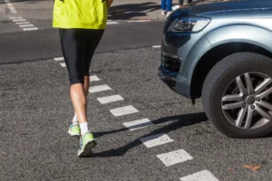 Close-Up Of A Pedestrian In Bright Athletic Clothing Crossing The Street In Front Of A Car, Used By A Dallas Pedestrian Accident Lawyer.