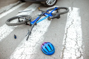A Fallen Blue Bicycle And Helmet On A Crosswalk After A Collision With A Car, Symbolizing The Need For An Oak Cliff Bicycle Accident Lawyer To Help Injured Cyclists Seek Compensation.